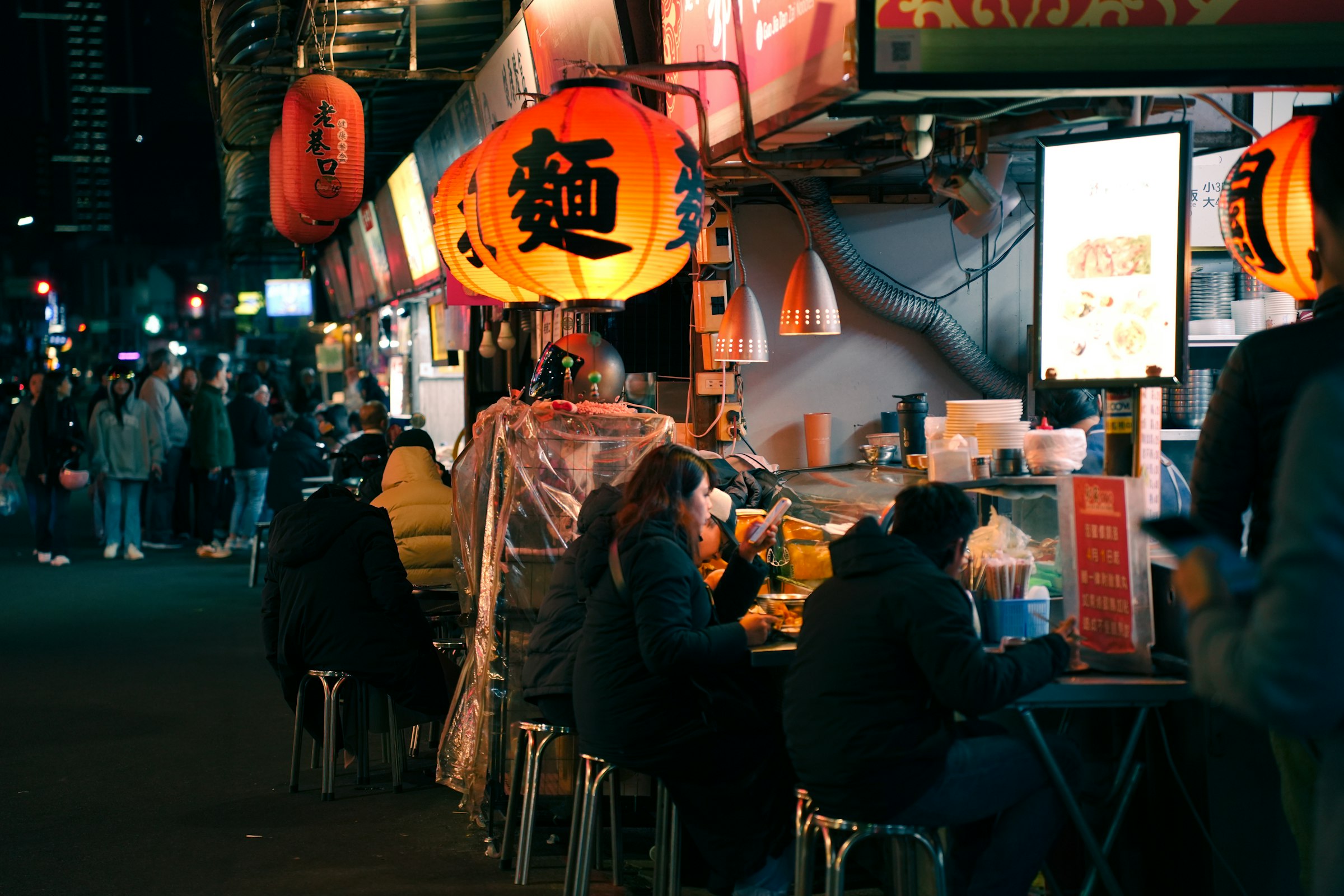 People eating at a lively night market food stall