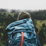 A solo traveler with a backpack looking out at a mountain view