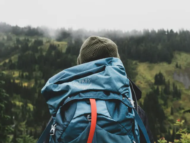 A solo traveler with a backpack looking out at a mountain view
