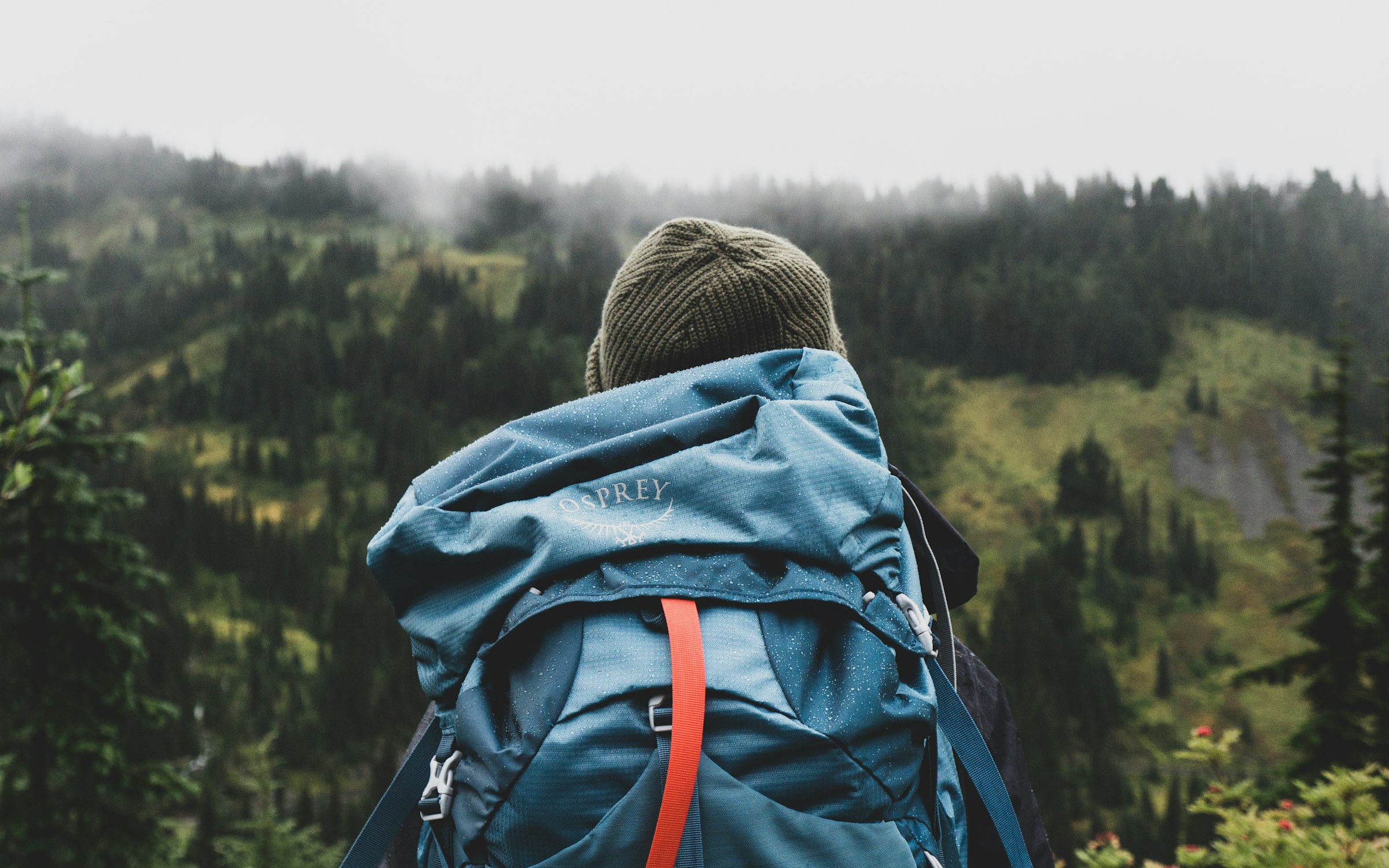 A solo traveler with a backpack looking out at a mountain view