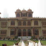 Front of Mohatta Palace in Clifton, Karachi, showing its pink and yellow stone domes and facade